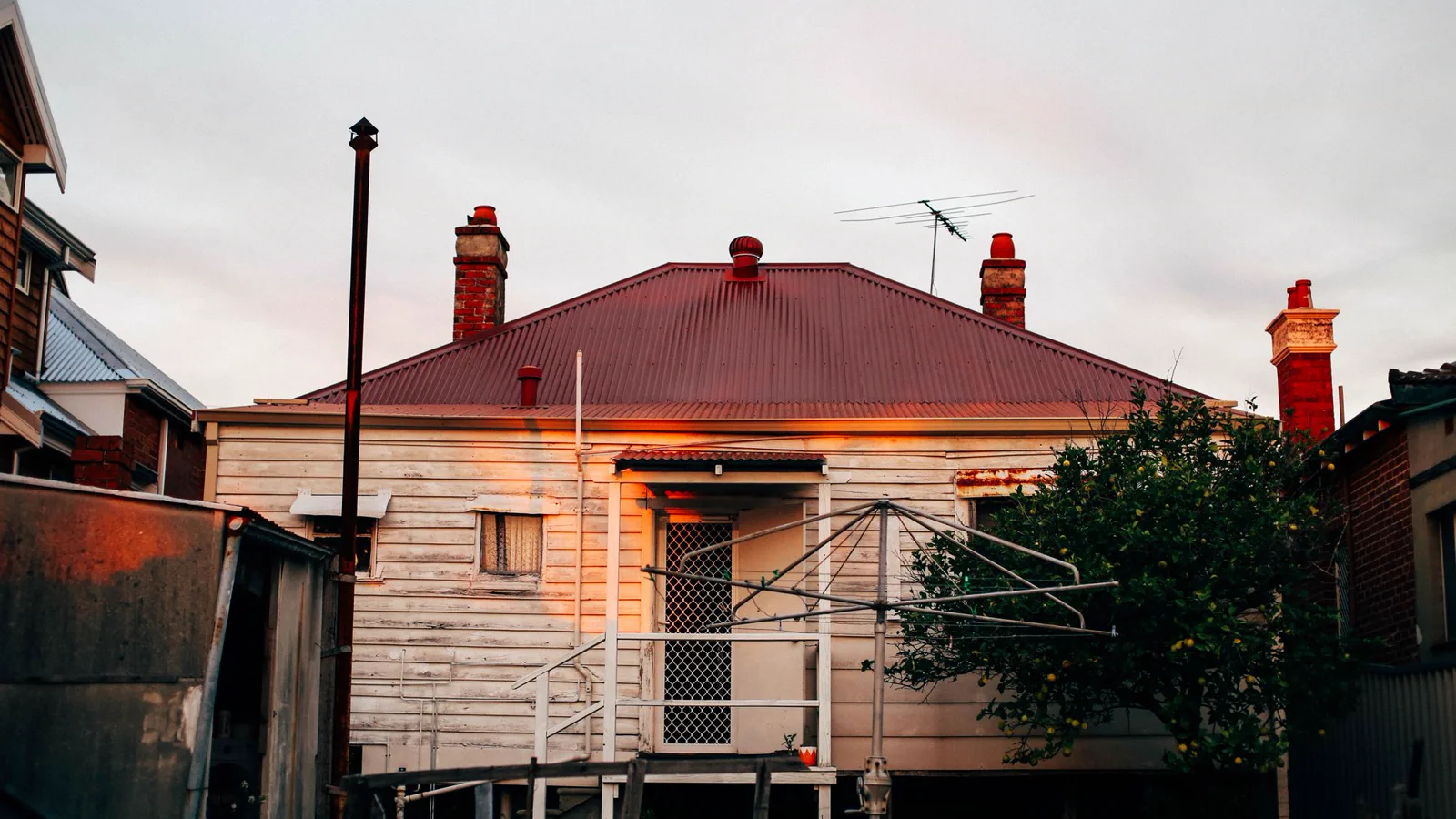 Old villa with a red iron roof, brick chimneys and weatherboard walls