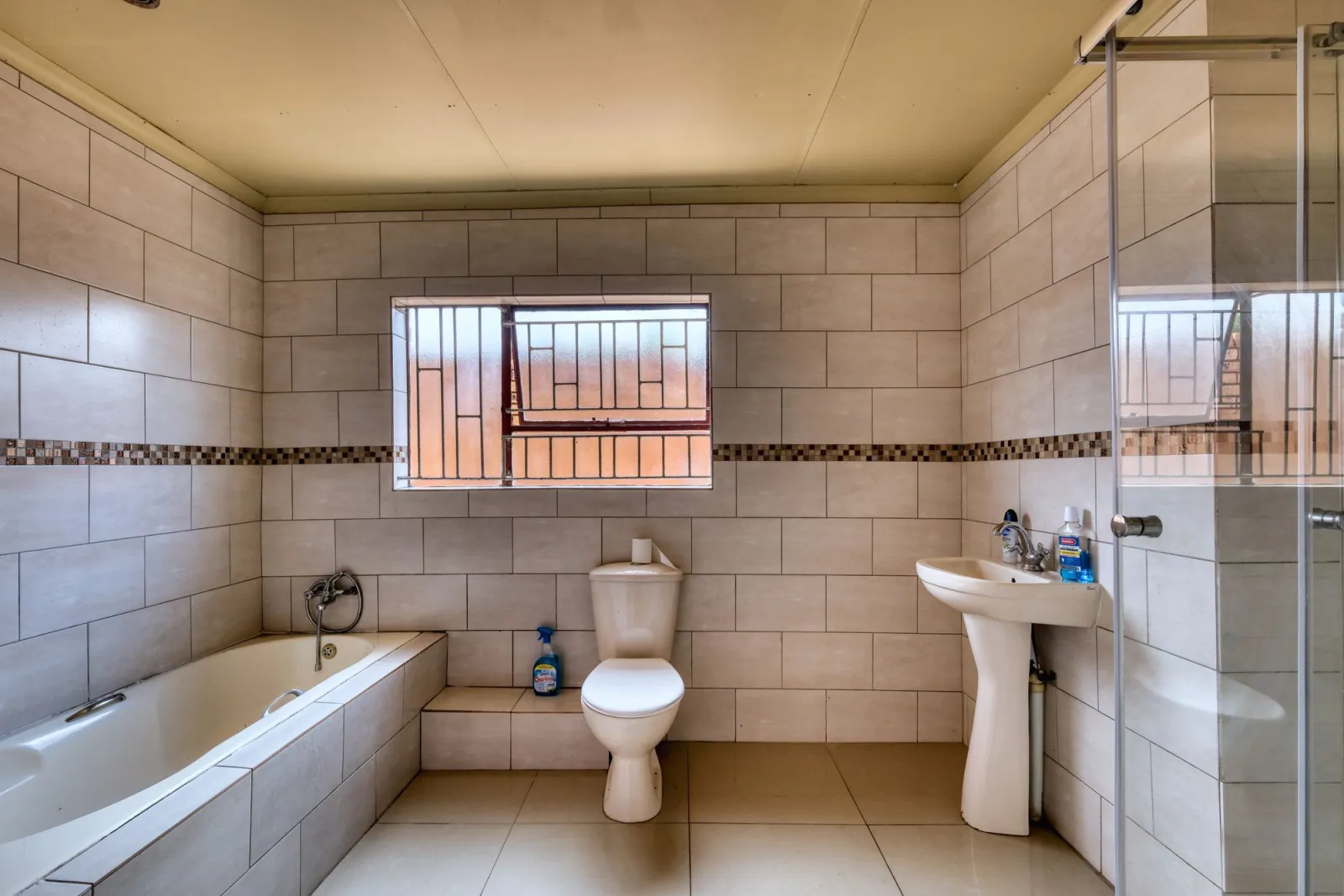 Bathroom with neutral tiling, bath, shower and modern fixtures