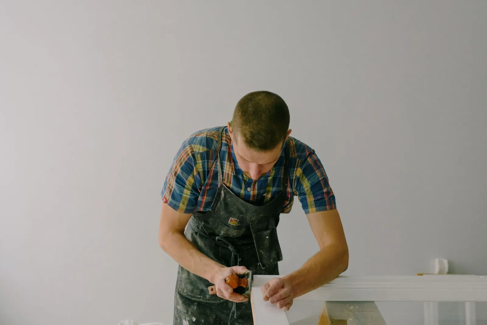 Carpenter sanding a timber board in a bright workshop