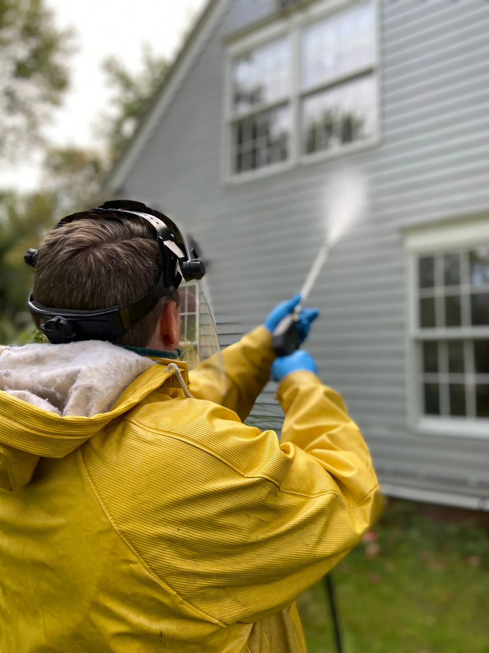 Person pressure washing exterior house cladding