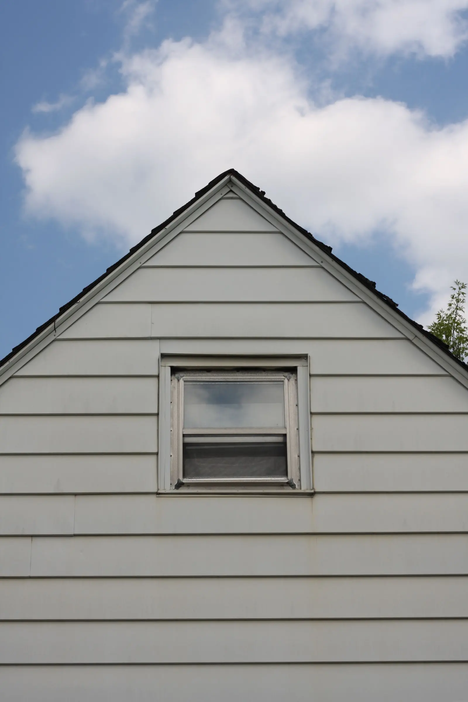 Painted weatherboard gable and window against a clear sky