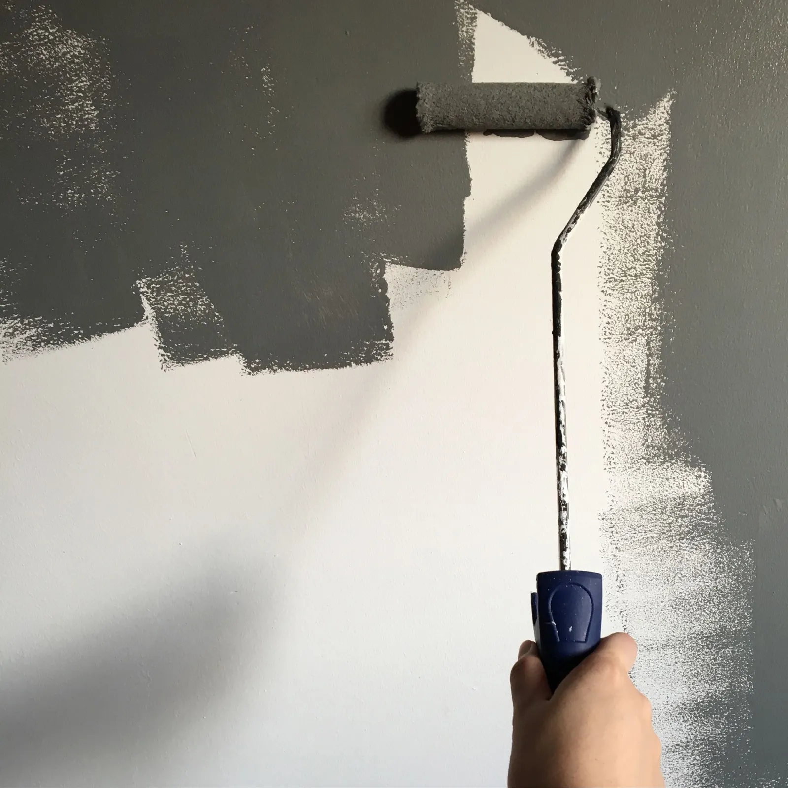 Paint roller applying a dark finish to an interior wall
