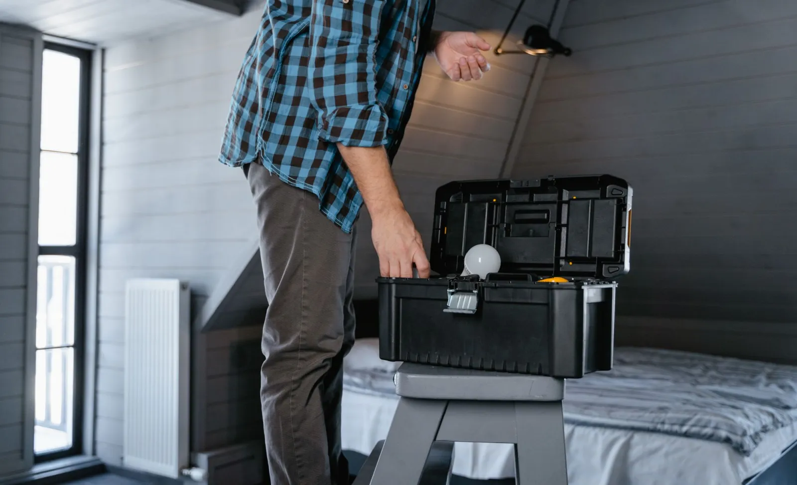 Tradesperson replacing a light fitting beside an open toolbox