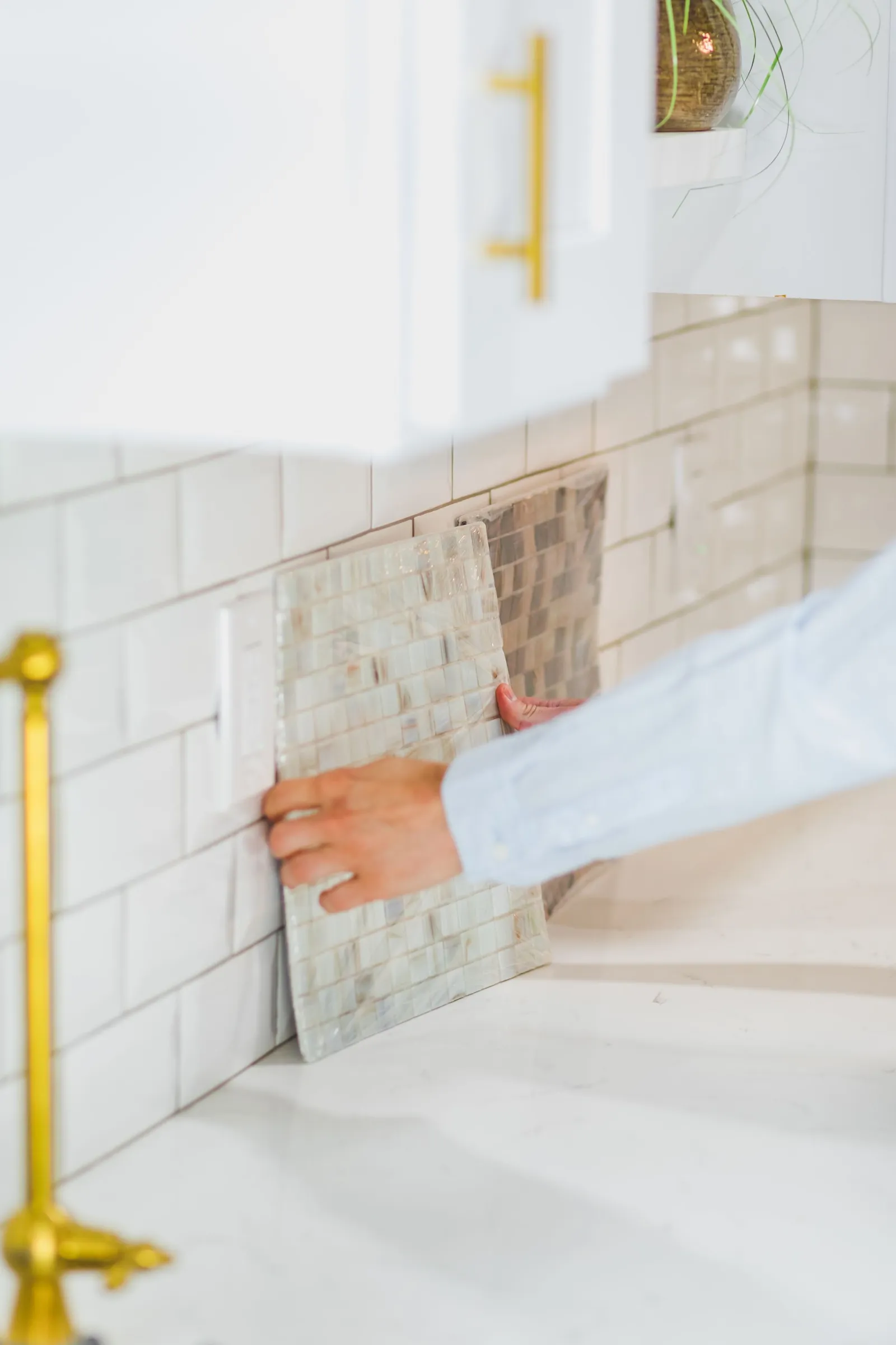 Person setting light wall tiles above a kitchen worktop