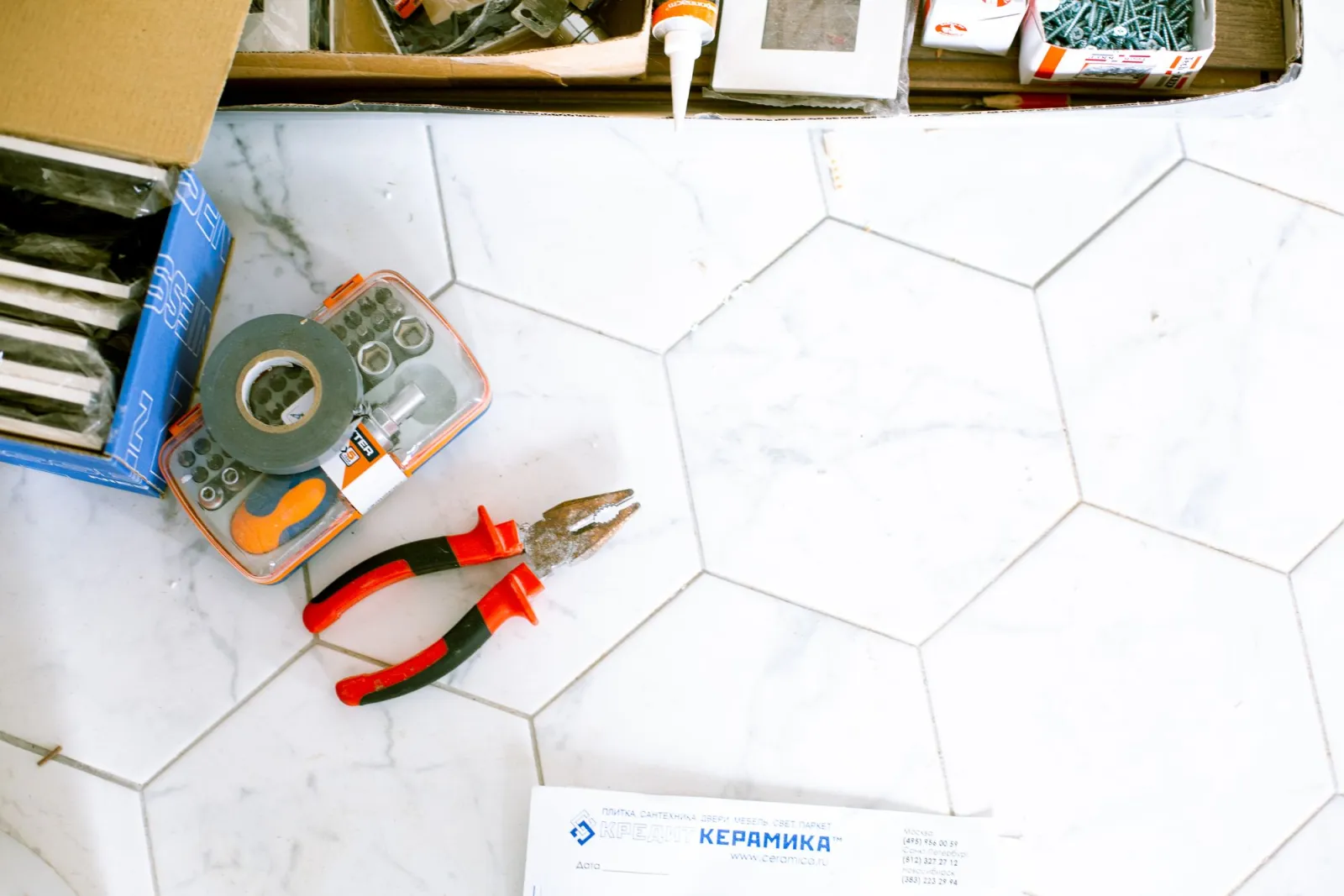Tiling tools arranged on a pale hexagonal tiled floor