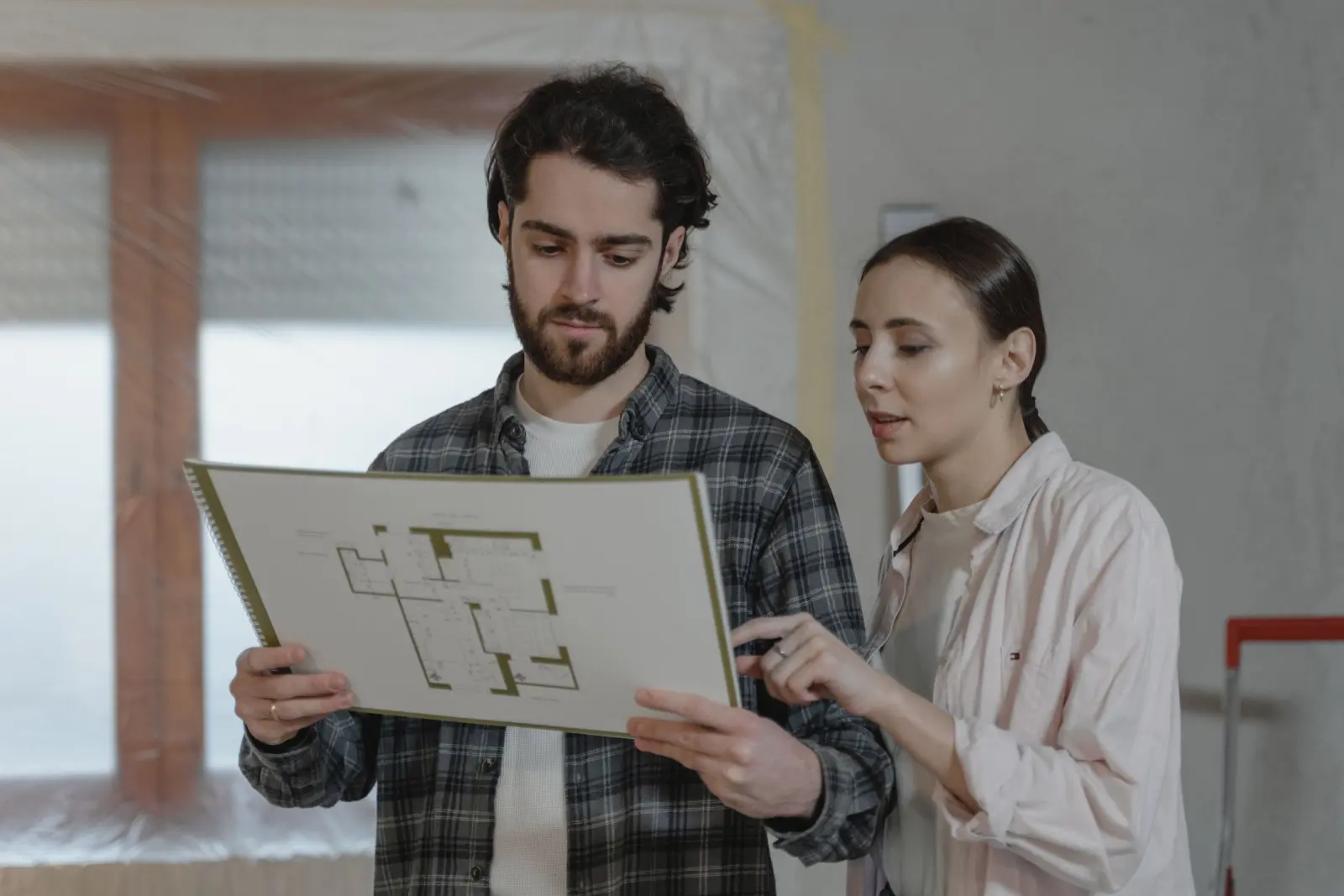 Two people reviewing a floor plan in a room prepared for work