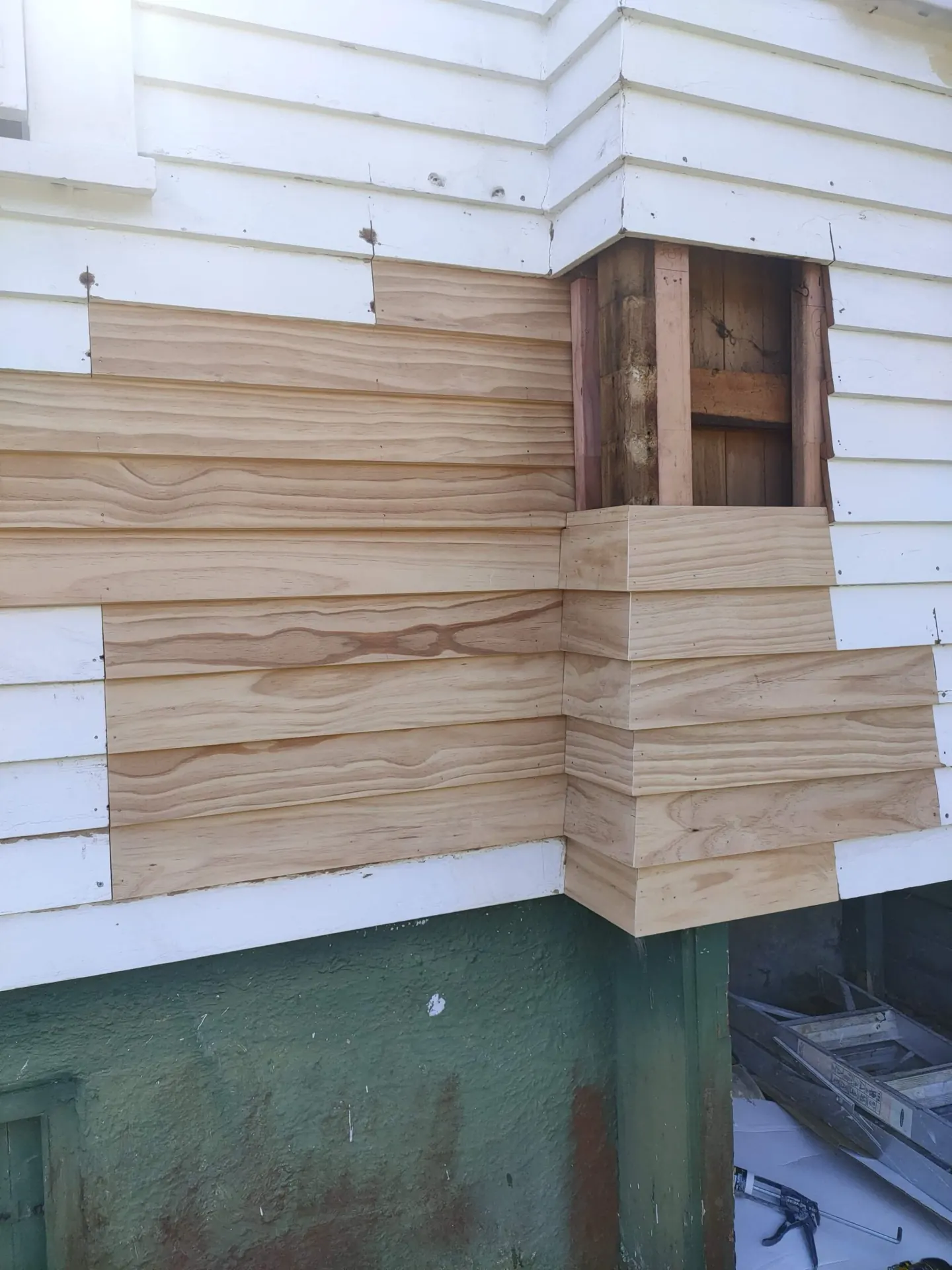 New timber weatherboards let into an old painted corner, ready for the final coat